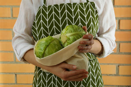 Woman hold fresh green cabbage against brick wallの写真素材