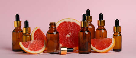 Dropper bottles with oil and grapefruit slices on pink backgroundの写真素材