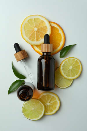 Dropper bottles with oil and citrus slices on white backgroundの写真素材