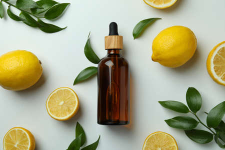 Dropper bottle with oil, lemons and leaves on white backgroundの写真素材