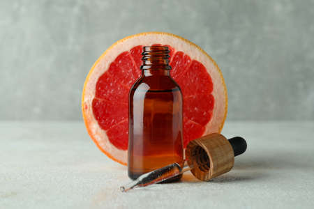 Dropper bottle with oil and grapefruit on white textured tableの写真素材