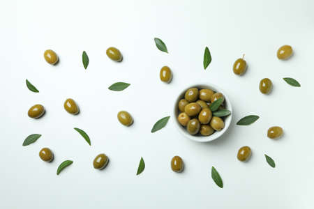 Bowl of green olives and leaves on white background, top viewの写真素材