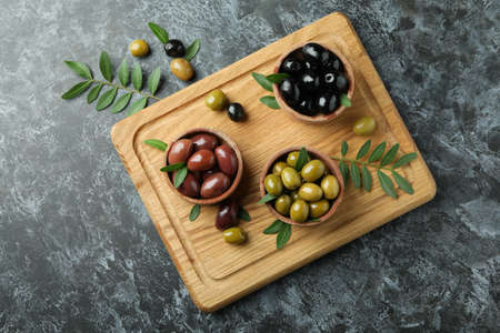 Board with olives and leaves on black smokey backgroundの写真素材