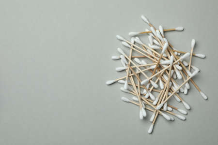 Wooden cotton swabs on light gray background, space for text