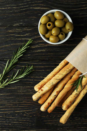 Craft paper with grissini, olives and rosemary on wooden backgroundの写真素材