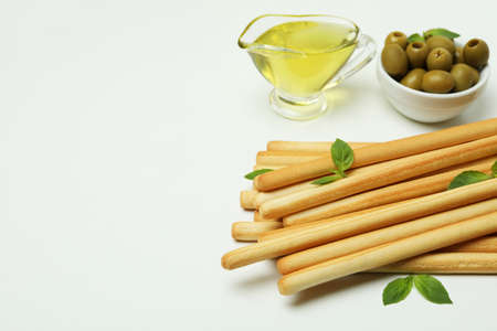 Grissini with basil, olives and oil on white background