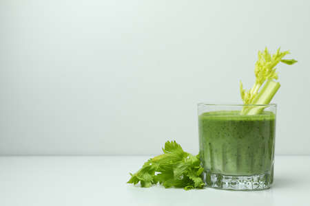 Glass of green smoothie with celery on white tableの写真素材