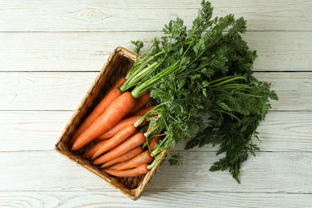 Basket with carrot on white wooden tableの写真素材