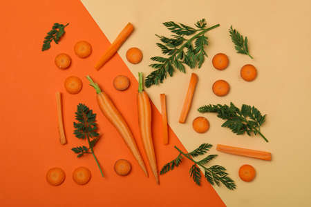Slices and leaves of fresh carrot on two tone backgroundの写真素材