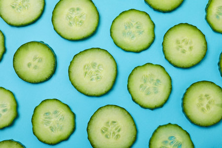 Fresh ripe cucumber slices on blue backgroundの写真素材