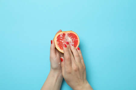Female hands hold grapefruit with condensed milk on blue background