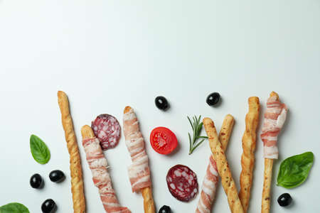 Grissini sticks with bacon and snacks on white backgroundの写真素材