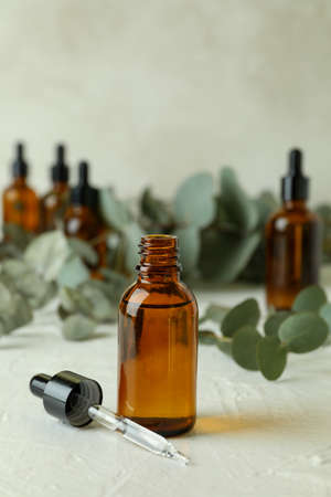 Bottles of eucalyptus oil and branches on white textured tableの写真素材