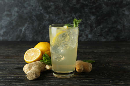 Glass of ginger - lemon drink and ingredients on wooden table