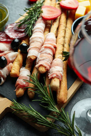 Board with grissini and snacks, and wine on black smokey tableの写真素材