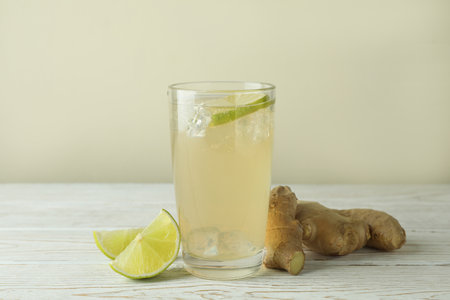 Glass of ginger beer and ingredients on white wooden tableの写真素材