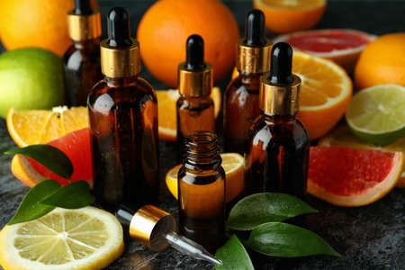 Dropper bottles with oil and different citrus on black smoky table