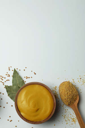 Bowl with mustard and spoon with powder on white backgroundの写真素材