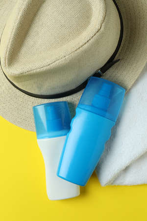 Hat, sunscreens and towel on yellow backgroundの写真素材
