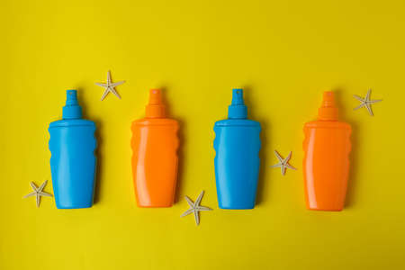 Bottles of sunscreen and starfishes on yellow backgroundの写真素材