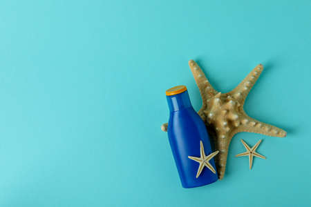 Blue bottle of sunscreen and starfishes on blue background