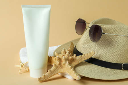 Sea accessories and sunscreen on beige background