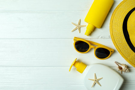 Summer concept with sunscreen on white wooden background