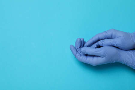Hands in medical gloves on blue background, space for text