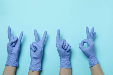 Hands in medical gloves with different gestures on blue background
