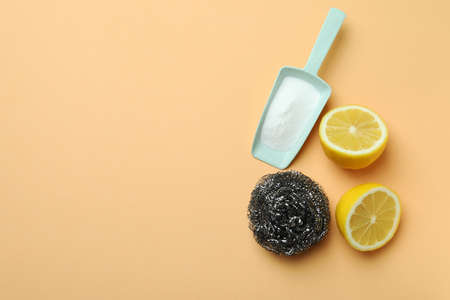 Scoop with acid powder, halves of lemon and metal sponge on beige background