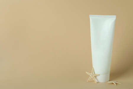 Tube of sunscreen and starfishes on beige background