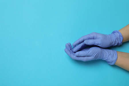 Hands in medical gloves on blue background, space for textの写真素材