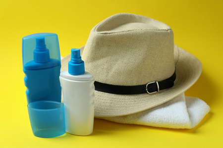 Hat, sunscreens and towel on yellow backgroundの写真素材
