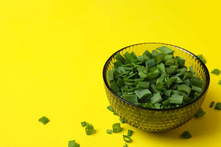 Bowl of chopped green onion on yellow backgroundの写真素材