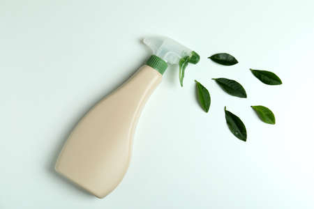 Blank detergent spray bottle and leaves on white backgroundの写真素材