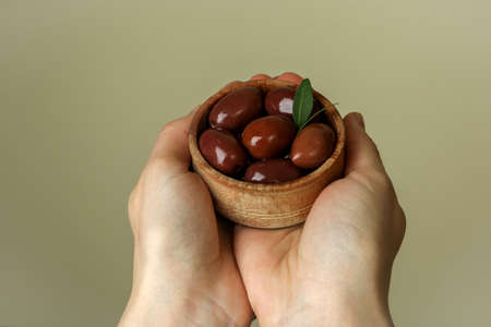 Female hands hold bowl of red olives