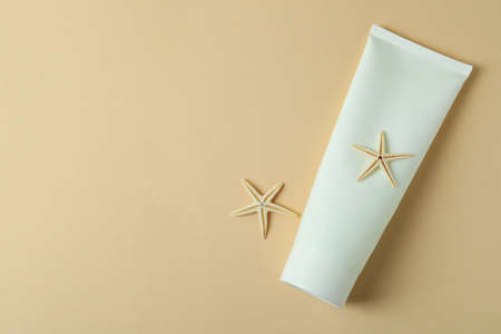 Tube of sunscreen and starfishes on beige background
