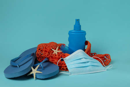 Bag with sea accessories, sunscreen and mask on blue background