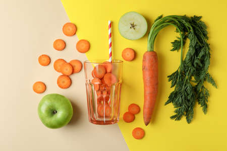 Glass and ingredients for apple - carrot juice on two tone backgroundの写真素材