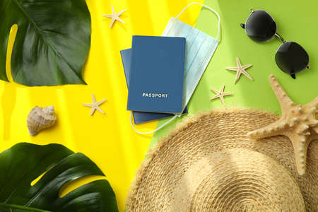 Passports with mask and vacation accessories on color background