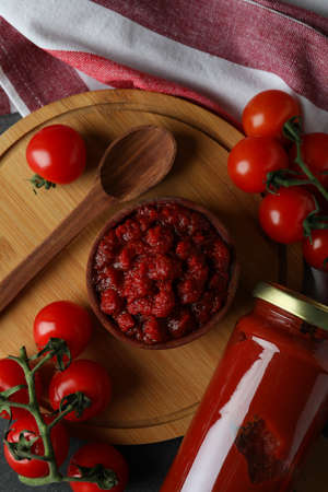 Bowl with tomato paste on dark wooden table with ingredients