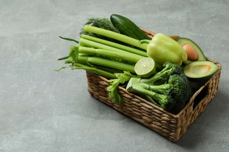 Basket with green vegetables on gray tableの写真素材
