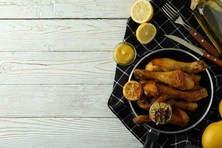 Concept of delicious eating with pan of roast chicken drumsticks on white wooden tableの写真素材