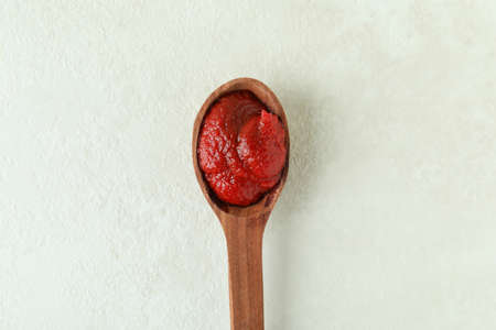 Wooden spoon with tomato paste on white textured backgroundの写真素材