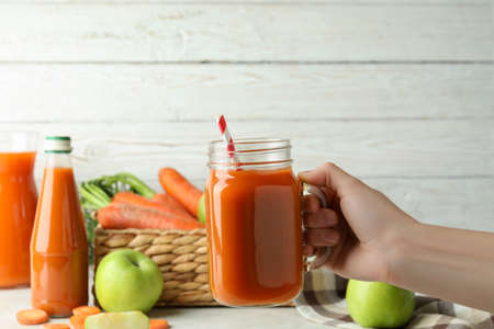Female hand hold jar with apple - carrot juiceの写真素材