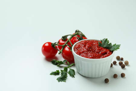 Bowl with tomato paste, tomatoes, pepper and parsley on white backgroundの写真素材