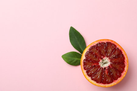 Half of red orange with leaves on pink backgroundの写真素材