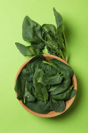 Bowl of spinach leaves on green backgroundの写真素材