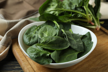 Bowl of spinach on cutting board on wooden tableの写真素材
