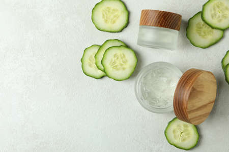 Jars with cosmetics and cucumber slices on white textured backgroundの写真素材